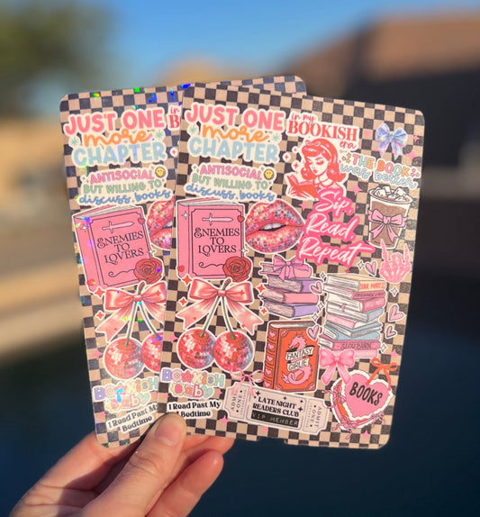 Hand holding Kindle e-reader case inserts with colorful stickers against a blurred outdoor background